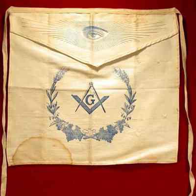 Apron: White cotton apron. 13" x 16" with printed Seing Eye on flap and Square and Compasses on body, all in blue print.