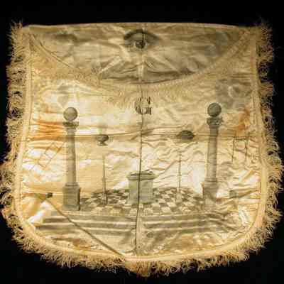 Apron, silk with decorations printed on it. White fringe. 12 3/4" x 14". Stains front and back