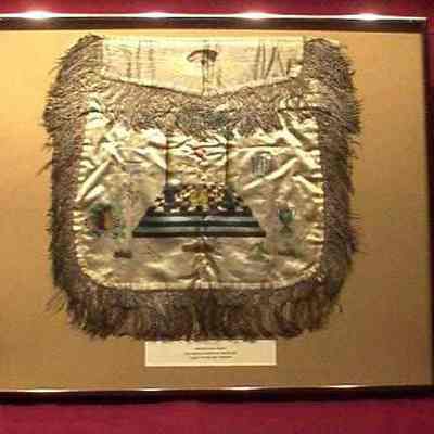 Apron: White silk with Masonic emblems in color print. Has silver tassels, All Seeing Eye on flap, blue backing. 14" x 16" framed