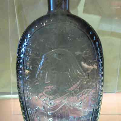 Flask: George Washington glask. The image of General Washington on one side and the American Eagle on the other. Purple glass, 8 3/4" high.