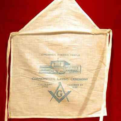 Apron: White cotton. Corner stone laying October 20, 1926, Cincinnati, Ohio. 12" x 11 1/2" with blue printing on front, picture of Temple, Square 7 Compasses