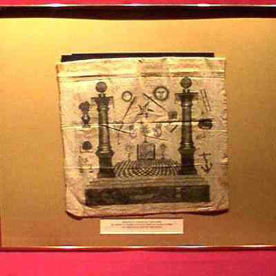 Apron: White print silk apron with Masonic emblems on front and flap. Worn by Calmes Lafayette Voight. 15" x 12 1/2"