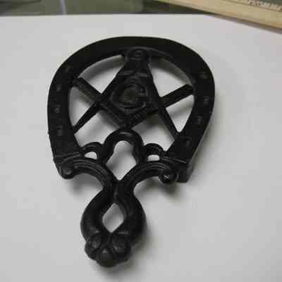 Trivet: Horseshoe shaped trivet made of cast iron with square and compass i center. Castin No. 267