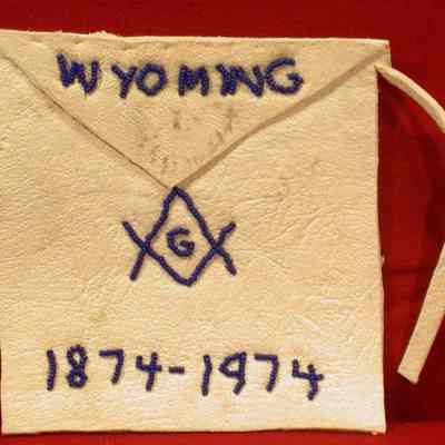 Apron: White lambskin apron with Wyoming, square & compasses, 1874-1974. 7 1/8" x 4 1/4"
