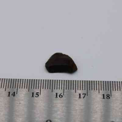 Basaltic glass core with ruler: The image shows a small, dark basaltic glass core placed next to a ruler for scale measurements.