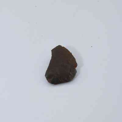 Closeup of basaltic glass core: The image showcases a small piece of basaltic glass core, displaying a dark, rough texture against a plain background.