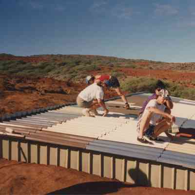 People painting top of water catchment structure