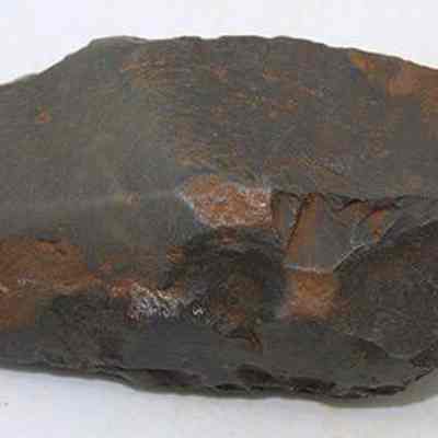 Profile of basalt adze (ko'i): The image shows a stone adze (ko'i) head, featuring a rugged and chipped surface, likely used in ancient woodworking or carving tasks.