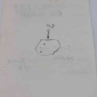 Back of artifact slip for basaltic glass flake: The image shows a slip of paper with faint notes and a simple diagram, possibly indicating an artifact's details, labeled with "S.P."