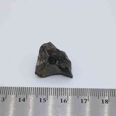 Closeup of basaltic glass core with ruler: A piece of basaltic glass core is placed next to a ruler, displaying its small size on a plain white background.