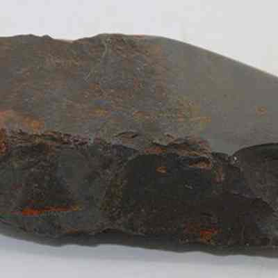 Profile view of a basalt adze (ko'i): The image shows a stone adze (ko'i) head with a rough, flaked appearance, likely used in ancient times for woodworking or carving tasks.