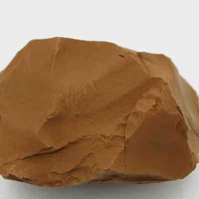 Closup of adze preform: The image shows an adze preform, crafted from brown stone, displaying rough, uneven surfaces and angular edges, indicative of early shaping techniques in tool making.