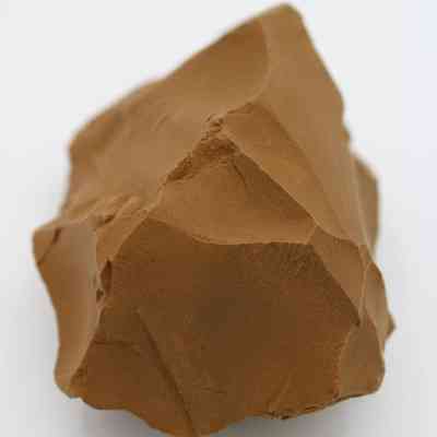 Closup of adze preform: The image depicts a roughly shaped, brown stone that serves as an adze preform, showing angular surfaces.
