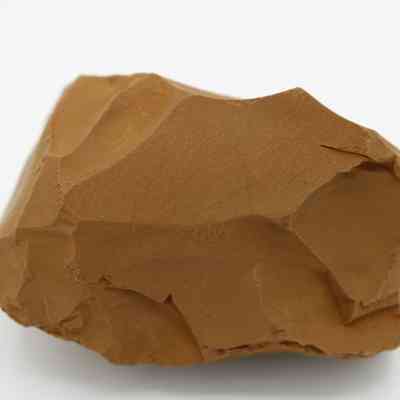 Close up of adze preform: The image shows a roughly hewn stone, resembling a preform for an adze, with flaked, sharp edges, and an irregular surface.