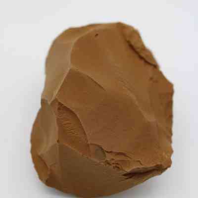 Closeup of adze preform: The image shows a rough, unfinished stone adze preform with visible chipping and a brownish hue.