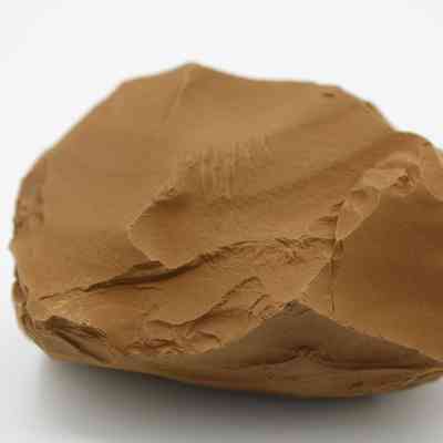 Closeup of adze preform: The image shows a stone adze preform, highlighted by its rough, unfinished surfaces and sharp edges, suggesting preliminary shaping for tool-making purposes.