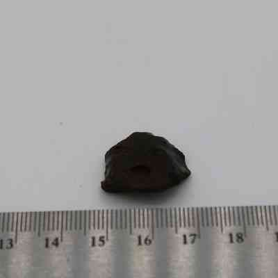 Glass flake with ruler: A small, dark glass flake is positioned beside a ruler for scale, indicating its size.