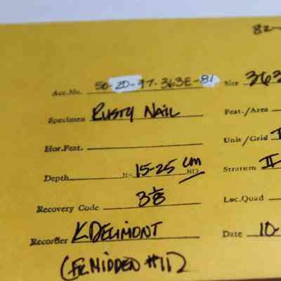 Artifact envelop for a rusty nail: The image shows a yellow envelope with handwritten information about a rusty nail specimen, including details like site, depth, and date.