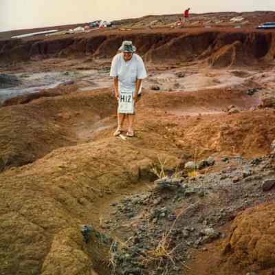 Person holding a sign near a potential burn site or archaeological site