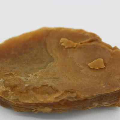 Closeup of an agate flake: The image shows a brown agate flake with distinct layers and rough edges, showcasing its natural, rustic texture and earthy tones.