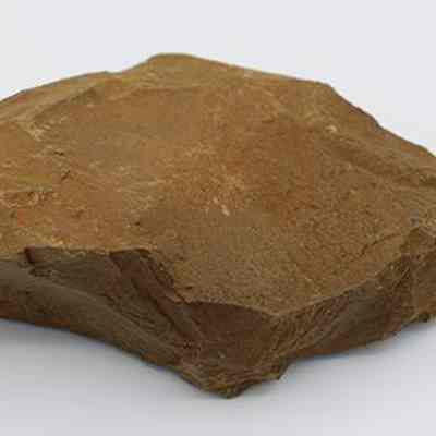 Closeup of basalt drill: The image shows a smooth, flat, brown rock drill with rough edges, sitting against a plain white background, showcasing its intricate natural texture and earthy tone.