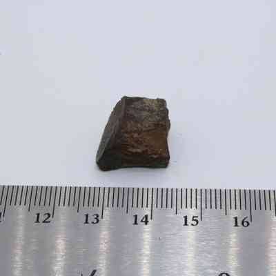 Glass core with ruler: A small, brown, irregularly shaped glass core is placed on a white surface next to a silver ruler for scale.