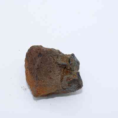 Closeup of basaltic glass core: The image shows a rough piece of basaltic glass core with uneven surfaces and dark earthy tones, indicating its natural volcanic origin.