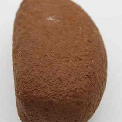 Closeup lengthwise view of breadloaf sinker: The image shows a small, smooth, brown a stone, commonly used as a sinker in fishing.