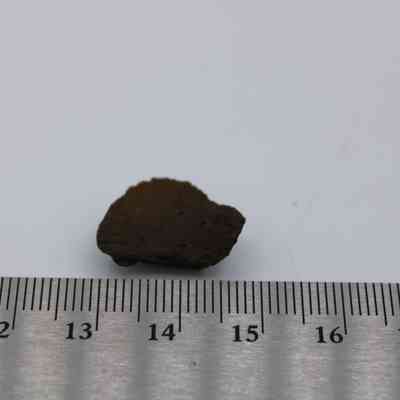 Basaltic glass core with ruler: The image shows a small piece of basaltic glass core placed next to a ruler, highlighting its size.