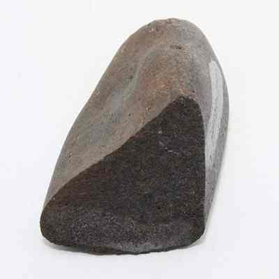 Closeup lengthwise view of hammerstone: The image shows an ancient hammerstone with a triangular shape, featuring a smooth, worn surface and a mixture of brown and gray hues.