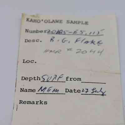 Front page of artifact slip for a basaltic glass flake: The image shows an artifact slip labeled "Kaho'olawe Sample" detailing sample number, description, depth, and date. It includes handwritten notes.