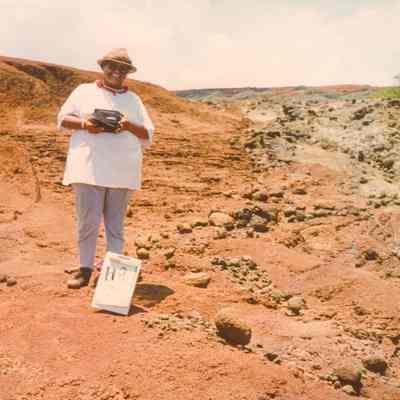 Smiling woman at white sign on hardpan terrain