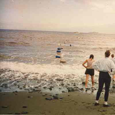 People on beach waiting for cargo from boat