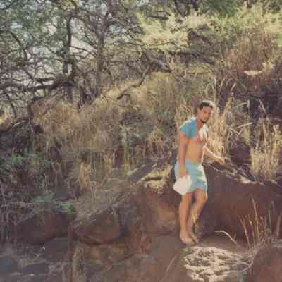 Man holding a bottle and standing on rock ledge
