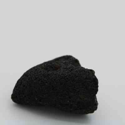 Profile of basaltic glass core: The image shows a dark, textured basaltic glass core with rough, uneven surfaces on a plain background.