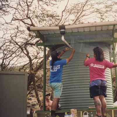 Men affixing mesh to top of a water storage structure