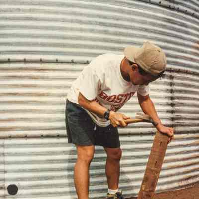 Man hammering nails into wooden plank