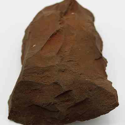 Lengthwise view of adze blank: The image shows a roughly shaped, reddish-brown stone tool with sharp edges and a textured surface, suggesting its use for cutting or scraping.