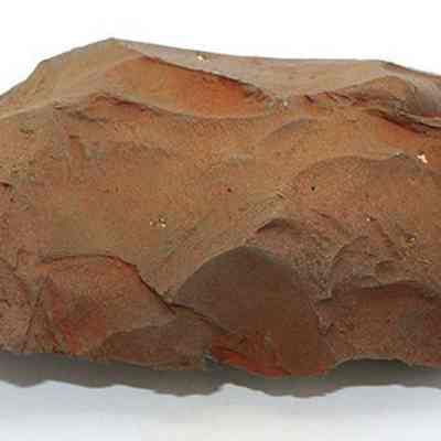 Profile of adze blank: The image shows a large, roughly shaped brown rock with jagged edges and a textured surface, resembling a tool or artifact possibly used in ancient times.