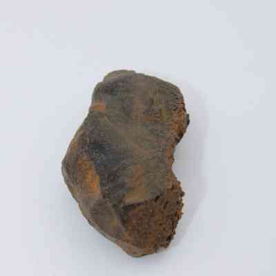 Closeup of glass flake: The image shows a rough, earth-toned glass flake with jagged edges, resting against a neutral, light background.