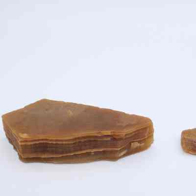 Two agate flakes: The image shows two brown agate flakes against a plain background, with distinct layers visible on the larger flake to the left.