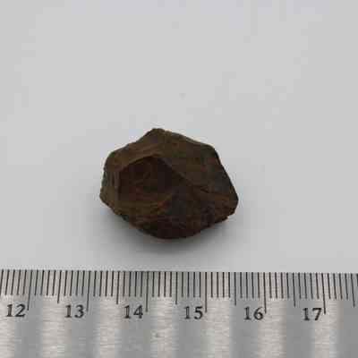 Basaltic glass core with ruler: A small basaltic glass core is placed on a white surface next to a metric ruler for scale.