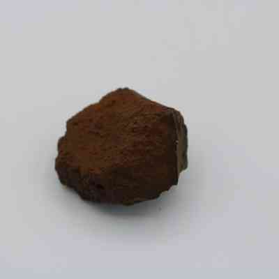 Closeup of basaltic glass core: The image shows a rough, angular piece of basaltic glass, featuring a deep brown color and a textured, rugged surface.