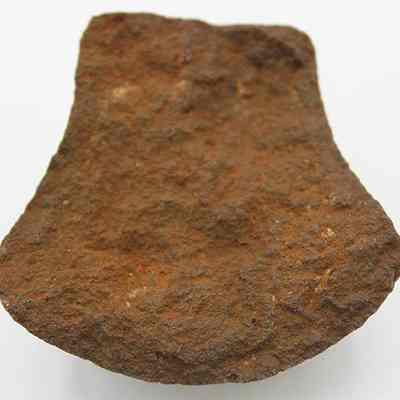 Broken side of grooved typed sinker or polishing stone: The image shows a close-up of a rough, weathered stone fragment possibly used as a sinker or polishing tool in ancient times.