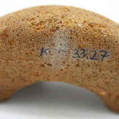 Closeup of fragment of cup or mortar with alternate id number visible: The image shows a curved, brown fragment of a cup or mortar with a rough surface. A number, possibly an inventory code is handwritten on one surface.