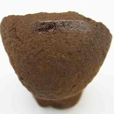The polished bottom of sinker or polishing stone w/alternate id # visible: The image shows a textured, dark brown stone fragment, possibly a sinker or polishing stone, with a number handwritten on its surface.