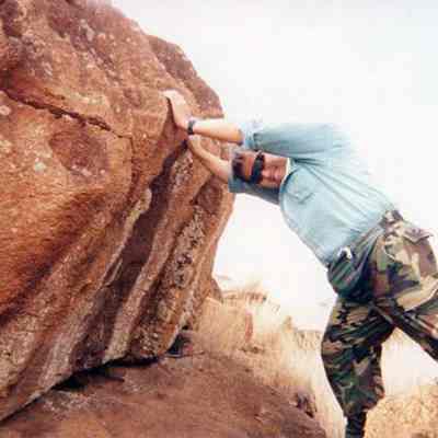 Derek Chow leaning on large pohaku (stone)