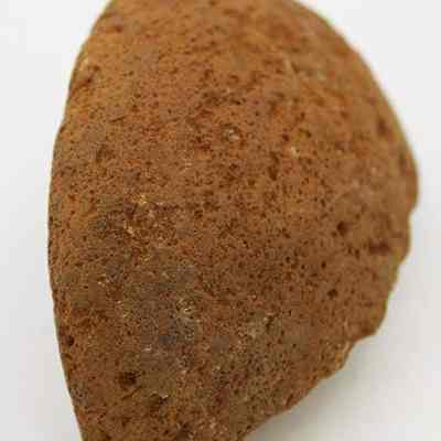 Closeup of a cup or mortar fragment: The image shows a rough, weathered fragment that could be part of a cup or a mortar, featuring a brown, textured surface.