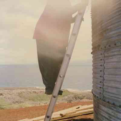 Person standing on ladder against water tank