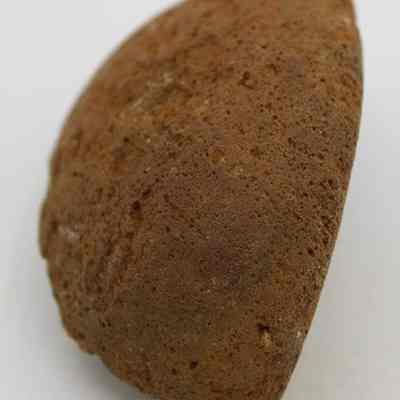 Closeup of cup or mortar fragment: The image shows a brown, rough-textured fragment, possibly from a cup or mortar, with a semicircular shape.